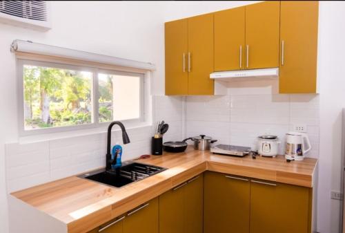a kitchen with yellow cabinets and a sink and a window at E and C tourist inn in Dumaguete