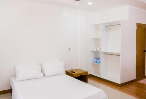 Habitación blanca con 2 camas y armario. en E and C tourist inn, en Dumaguete