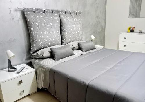 um quarto com uma cama grande com lençóis e almofadas cinzentos em sciuliddA Casa Vacanze em Avola