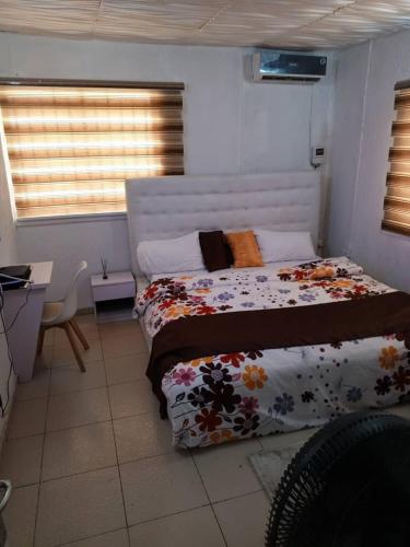 - une chambre avec un lit et une couette à fleurs dans l'établissement Triple Dee Shortlet Apartments, Omole phase 1, Lagos, à Lagos