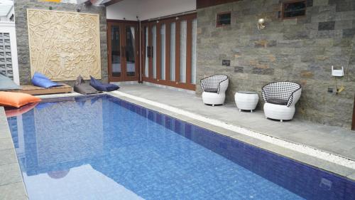 una piscina con tre sedie e una piscina di Namira Paradise Garden a Banjarbaru