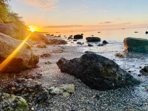a sunset on a beach with rocks and the ocean at Bon Vivant Front de Mer - Ile Rodrigues in Rodrigues Island