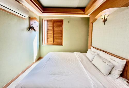 a bedroom with a bed with white sheets and pillows at Prada motel in Geoje 