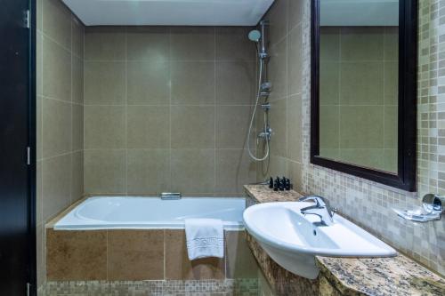 a bathroom with a tub and a sink at DIFC 1BR at SkyGardens Tower in Dubai