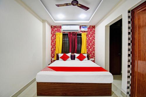 a bedroom with a bed with red and yellow curtains at OYO Flagship Aarvi Palace in Cuttack