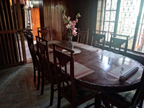 uma mesa de madeira com cadeiras e um vaso de flores em Maliga Inn em Gampola