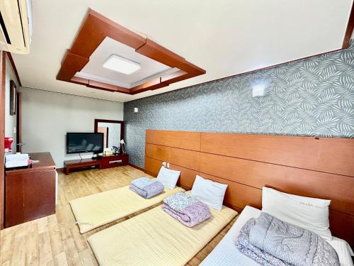 a room with two beds and a tv at Prada motel in Geoje 