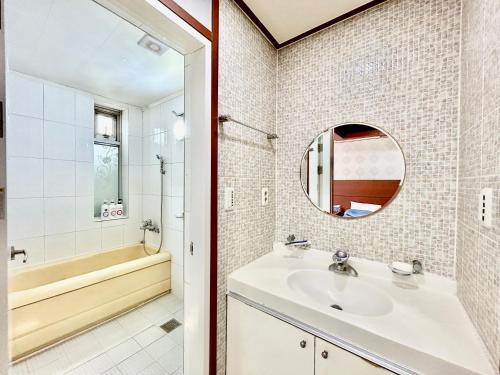 a bathroom with a sink and a tub and a mirror at Prada motel in Geoje 