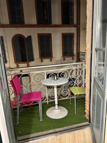 uma mesa e cadeiras numa varanda com uma mesa em Apparemment cosy et chaleureux em Montauban