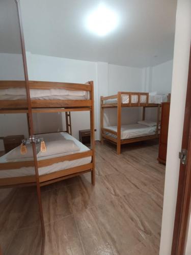 a room with two bunk beds and a hallway at Mini Hostal Cardos in Pisco