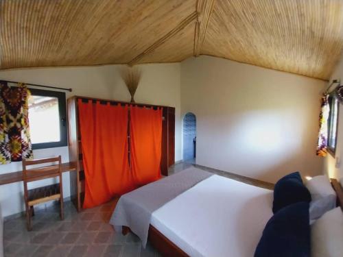 una camera da letto con un grande letto con una tenda arancione di Kato William a Nialon