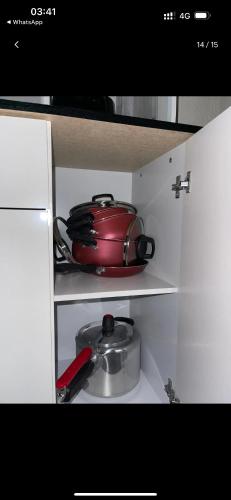 a red tea pot and a pan in a cabinet at Apartamento MRV perto da musiva in Várzea Grande