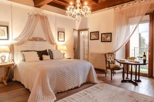 1 dormitorio con cama, mesa y lámpara de araña en LA FINESTRA SUL BORGO Dimora Storica, en Laterina