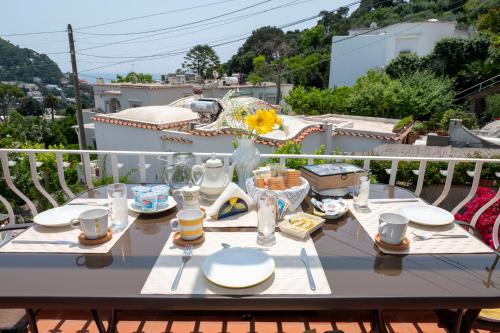 une table avec des assiettes et des verres sur un balcon dans l'établissement Casa Rubina, à Capri