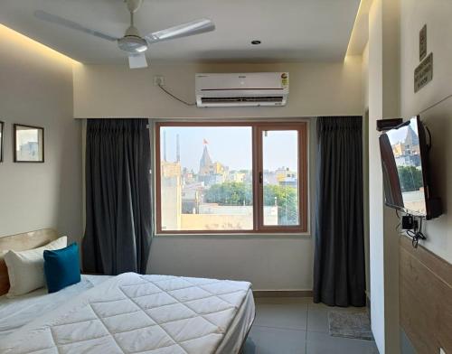 a bedroom with a bed and a large window at Hotel Kant by GoHotels - Best Hotel Near Shree Dwarkadhish Temple in Dwarka