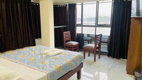 1 dormitorio con 1 cama y algunas sillas y ventanas en Manu's Home Stay, en Malayāttūr
