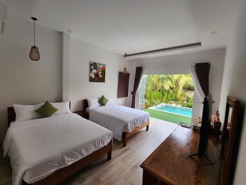 a bedroom with two beds and a television and a pool at Ninila Villa Phu Quoc in Phu Quoc