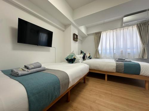 a hotel room with two beds and a flat screen tv at nestay miriz tokyo ikebukuro in Tokyo
