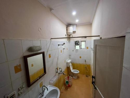 y baño con 2 aseos, lavamanos y espejo. en Varal Mane en Bangalore