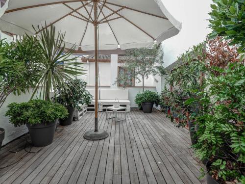 un ombrello su una terrazza di legno con piante di Beach Villa Aralinn by Hello Homes Sitges a Sitges