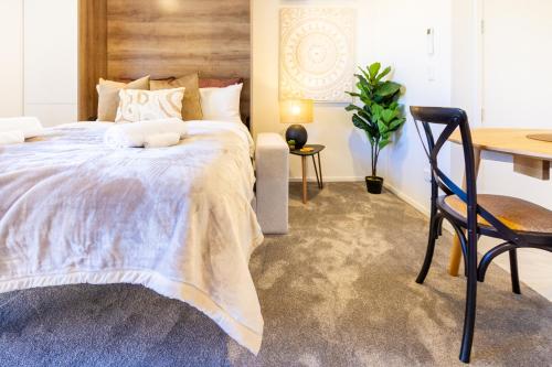 a bedroom with a bed and a desk and a chair at Central Oasis: Charming Studio with Backyard in Christchurch