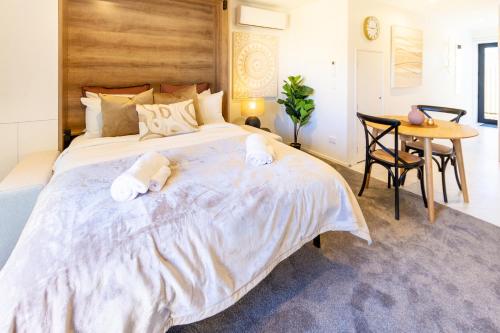 a bedroom with a large bed and a table at Central Oasis: Charming Studio with Backyard in Christchurch