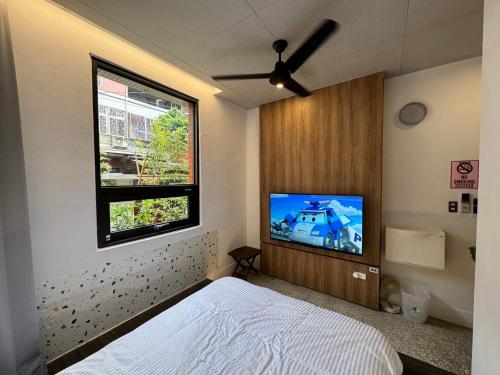 a bedroom with a bed and a flat screen tv at 拾號行旅民宿 in Chung-shan