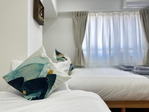 a bedroom with two beds with white sheets and a window at nestay miriz tokyo ikebukuro in Tokyo