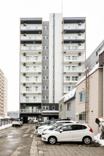 a parking lot with cars parked in front of a building at Shizuk +O Stay 2 in Kita-sanjō