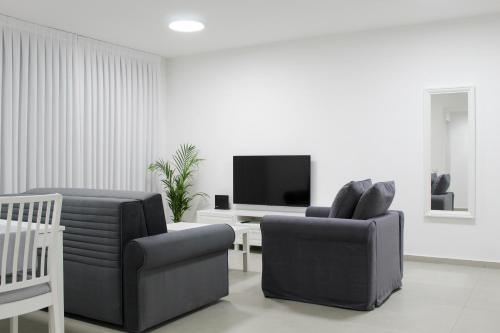 a living room with two chairs and a television at Luxury Penthouse #46 By Hashdera Eilat in Eilat