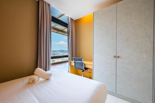 a bedroom with a bed and a window and a desk at Greystone 99 Suites in Melaka