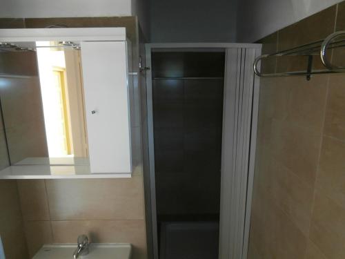 een badkamer met een douche, een spiegel en een wastafel bij River Studios & Apartments in Mesongi