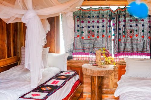 1 dormitorio con 2 camas, mesa y cortinas en Homestay Chu Vang en Phong Thổ