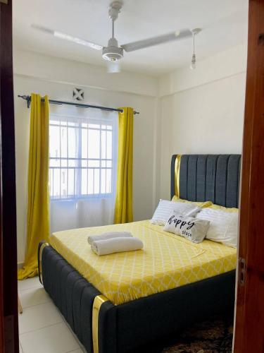 een slaapkamer met een bed met gele lakens en een raam bij Ample home 2 bedroom apartment in Mombasa