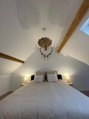 um quarto com uma grande cama branca e um lustre em Beau duplex vue sur le Lac Blanc em Orbey