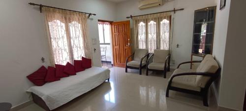 a living room with a couch and chairs and windows at Suburbs Holiday Home in Dabolim