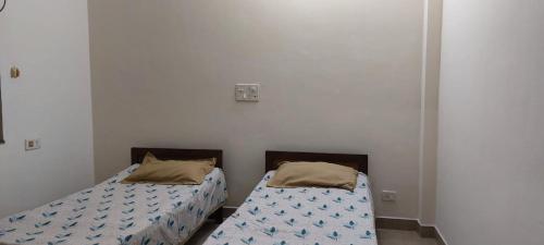 two beds in a room with white walls at Suburbs Holiday Home in Dabolim