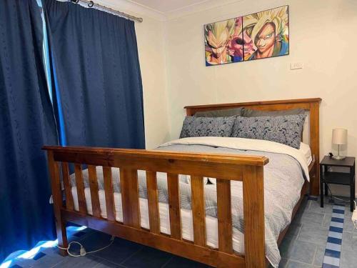 a bedroom with a wooden bed with blue curtains at Penrith Relaxing Beauty 3BR Entire House Sleep 8 in Penrith
