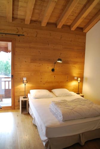 a bedroom with a bed with a wooden wall at Chalet le Réconfort, accès skis aux pieds in Saint-François-Longchamp