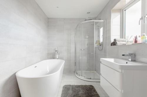 a white bathroom with a tub and a sink at Bed and breakfast near Truro and the A30 in Truro