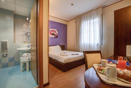 a hotel room with a bed and a table and a bathroom at Hotel Europa in Ancona