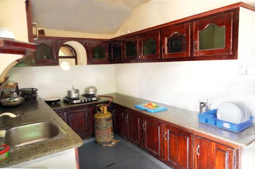 a kitchen with wooden cabinets and a sink at St. Mary Houseboat in Kumarakom
