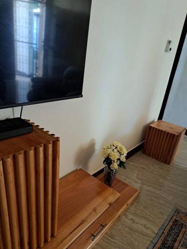 a vase of flowers sitting on a table in front of a television at Ellyz Home Stay in Moshi