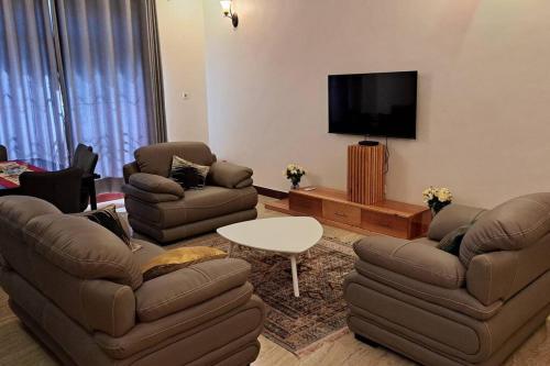 sala de estar con 2 sofás y TV de pantalla plana en Ellyz Home Stay en Moshi