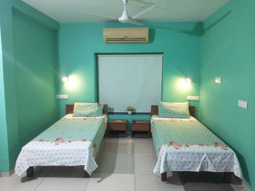 two beds in a room with green walls at A Private Room With Terrace in Ahmedabad
