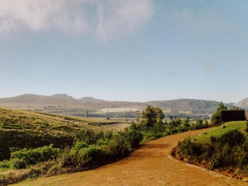 a dirt road in a field with mountains in the background at Highlands Lodge Mountain Retreat in George