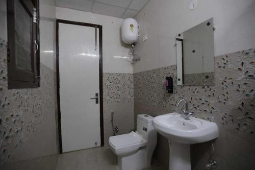 a bathroom with a sink and a toilet and a mirror at PLAY Grand Imperial Sector 18 - Couple friendly in Noida