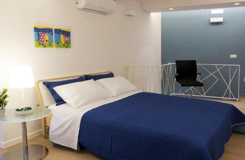 1 dormitorio con 1 cama azul y 1 silla en Lùre Holiday Napoli, en Nápoles
