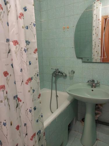 a bathroom with a sink and a tub and a shower curtain at Велика 1к квартира біля метро Лівобережна вулиця Флоренції 1 in Kyiv