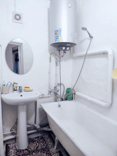 a white bathroom with a sink and a tub and a mirror at DADOW Apartments in Naryn